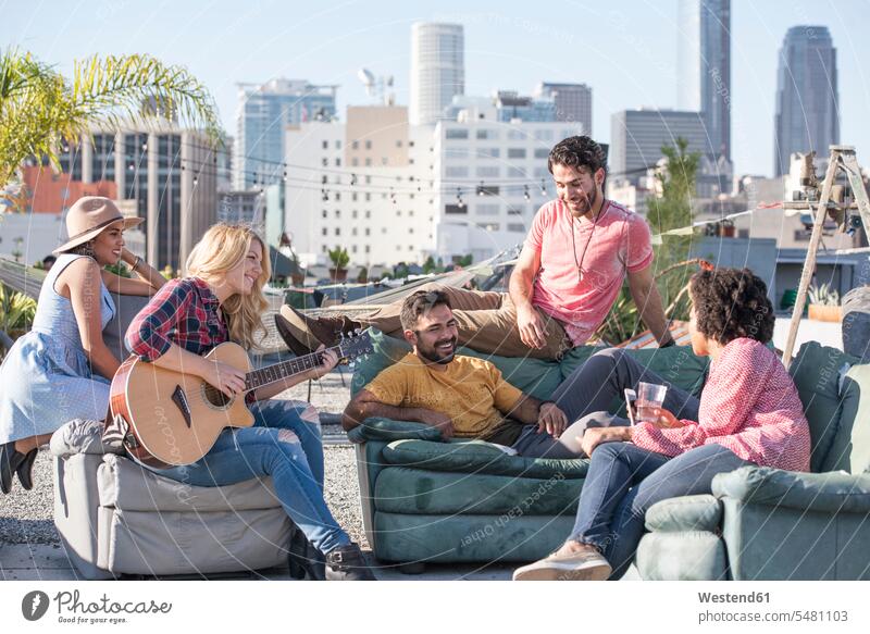 Friends having a rooftop party and playing guitar roof terrace deck laughing Laughter Party Parties friends guitars celebrating celebrate partying positive