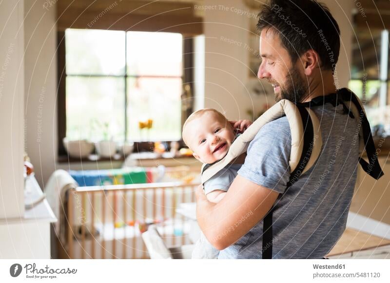 Happy father with baby in baby carrier at home babies infants Baby Carrier Baby Harness happiness happy pa fathers daddy dads papa people persons human being