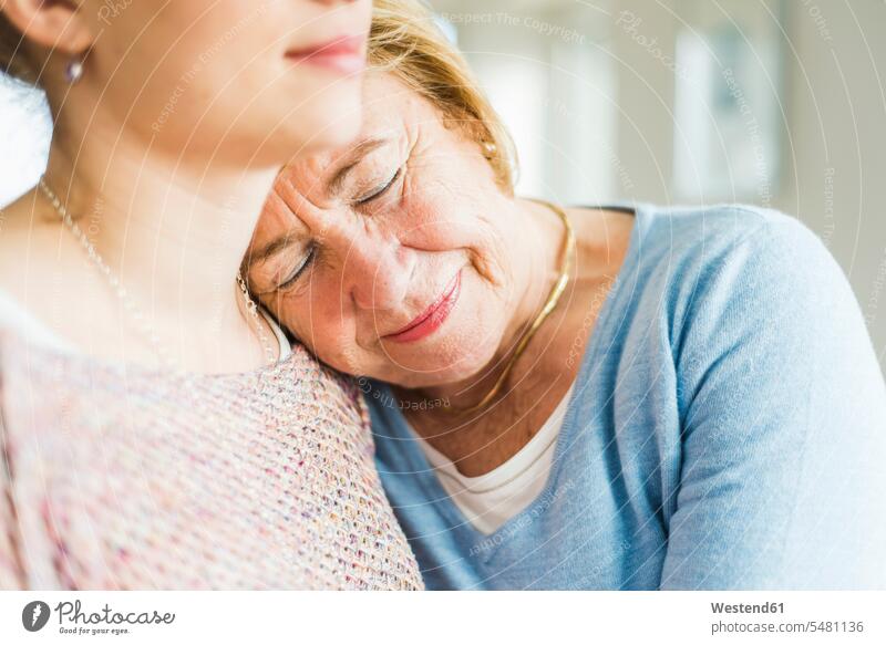 Senior woman with closed eyes leaning against young woman's shoulder caucasian caucasian ethnicity caucasian appearance european indoors indoor shot Interiors