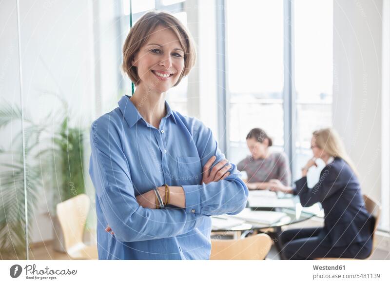 Portrait of smiling businesswoman with colleagues in background caucasian caucasian ethnicity caucasian appearance european Germany indoors indoor shot