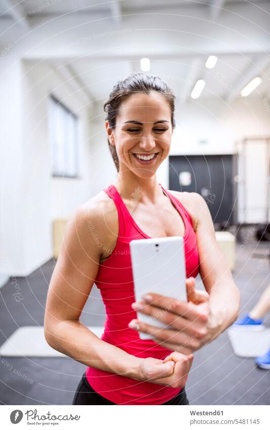 Young female athete taking selfies in gym gyms Health Club sharing share Selfie Selfies fit athlete sportswoman athletes female athlete sportswomen