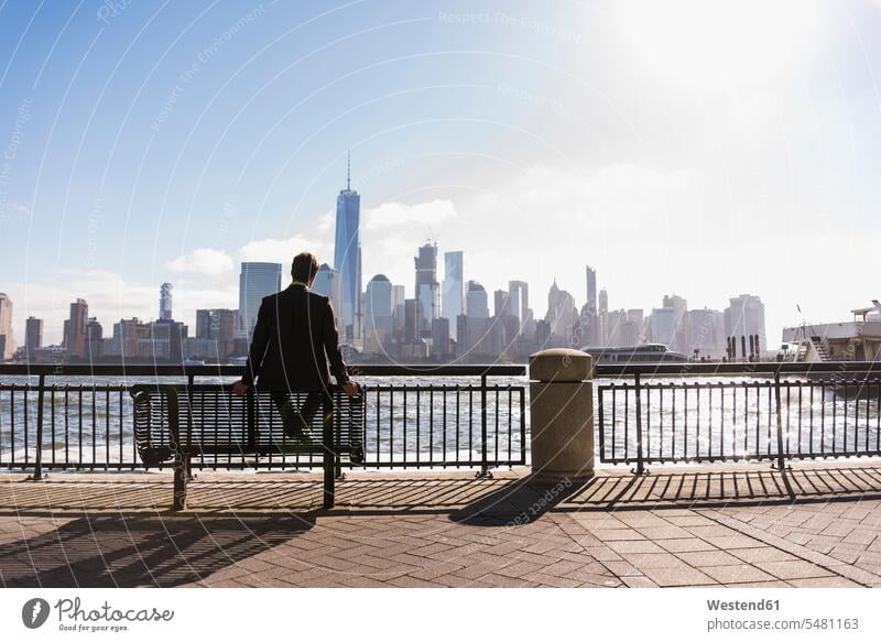 USA, man sitting on bench at New Jersey waterfront with view to Manhattan -  a Royalty Free Stock Photo from Photocase