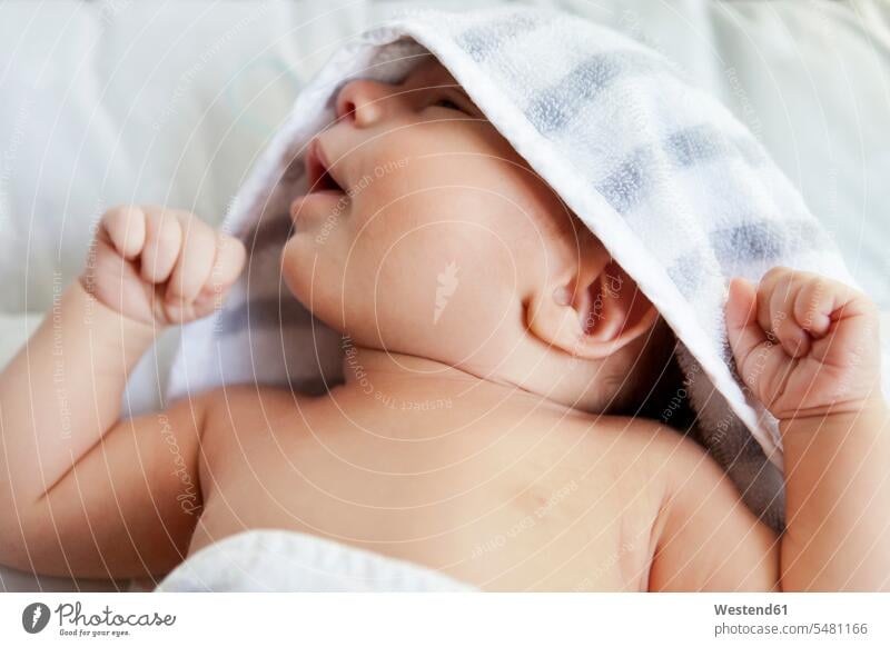 Close-up of baby wrapped in a towel after taking a bath towels lying laying down lie lying down Wrapped Up babies infants people persons human being humans
