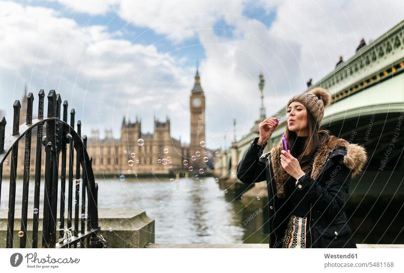 UK, London, young woman blowing soap bubbles bubble ring bubble rings City Break City Trip Urban Tourism woolly hat Wooly Hat Knit-Hat Knit Hats wool cap