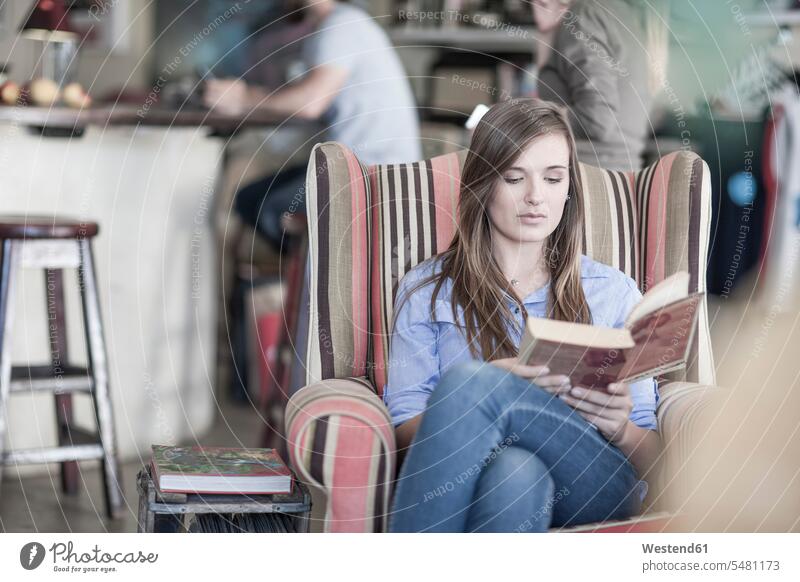 Young woman sitting in coffee shop reading book caucasian caucasian ethnicity caucasian appearance european three-quarter length three quarter length armchair