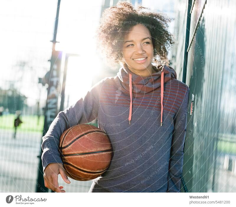 Portrait of smiling young woman with basketball at backlight Mixed Race Person mixed-race Person mixed race ethnicity sportive sporting sporty athletic