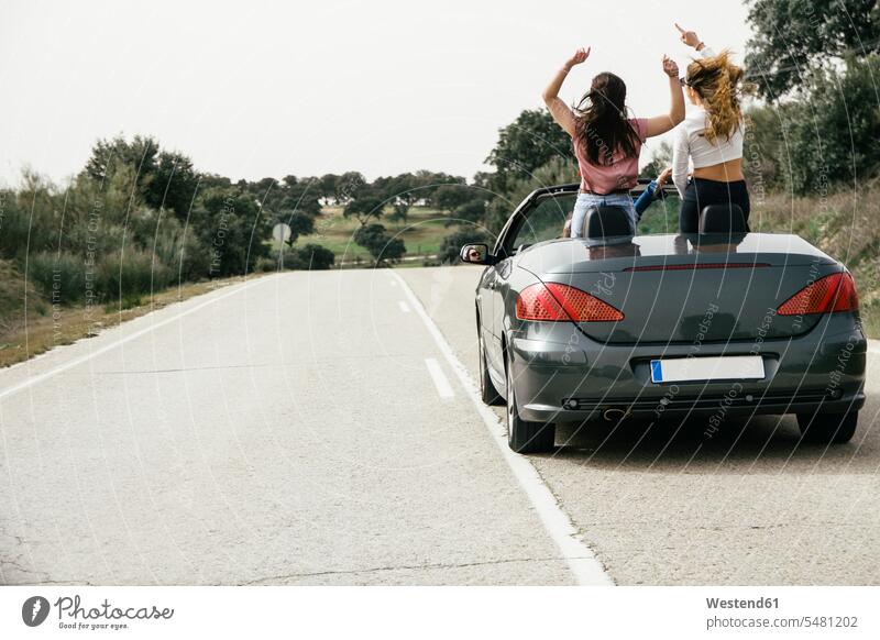 Women having fun in a convertible car on a country road Spain mischief rampaging rampage Travel automobile Auto cars motorcars Automobiles messing about silly