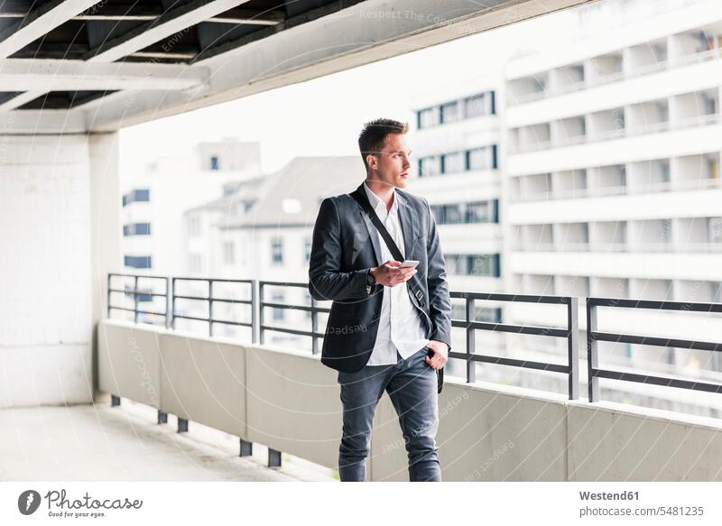 Young businessman using smartphone, walking on parking level Smartphone iPhone Smartphones Businessman Business man Businessmen Business men call telephone call