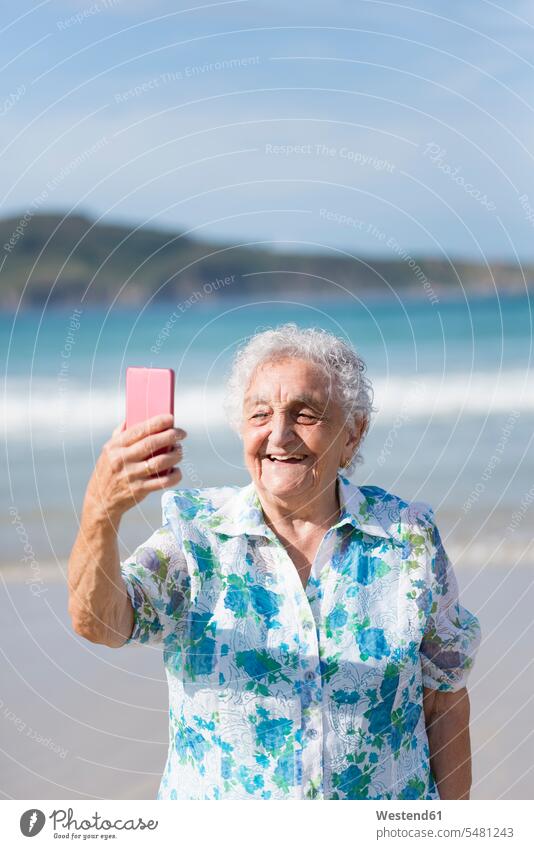 Happy senior woman taking selfie on the beach Selfie Selfies senior women elder women elder woman old photographing senior adults females Adults grown-ups