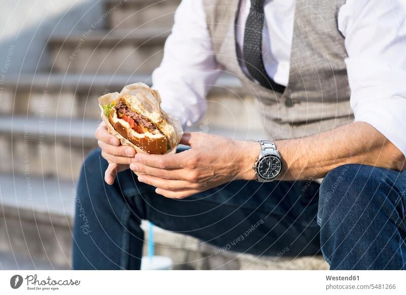 Businessman in the city sitting on stairs eating a hamburger Business man Businessmen Business men break stairway business people businesspeople business world