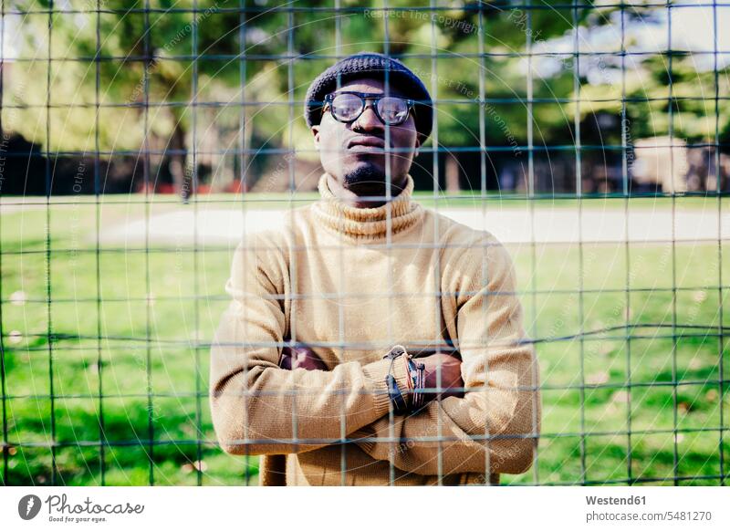 Portrait of a cool young man behind a metal net men males portrait portraits serious earnest Seriousness austere cool attitude composed coolness laid-back