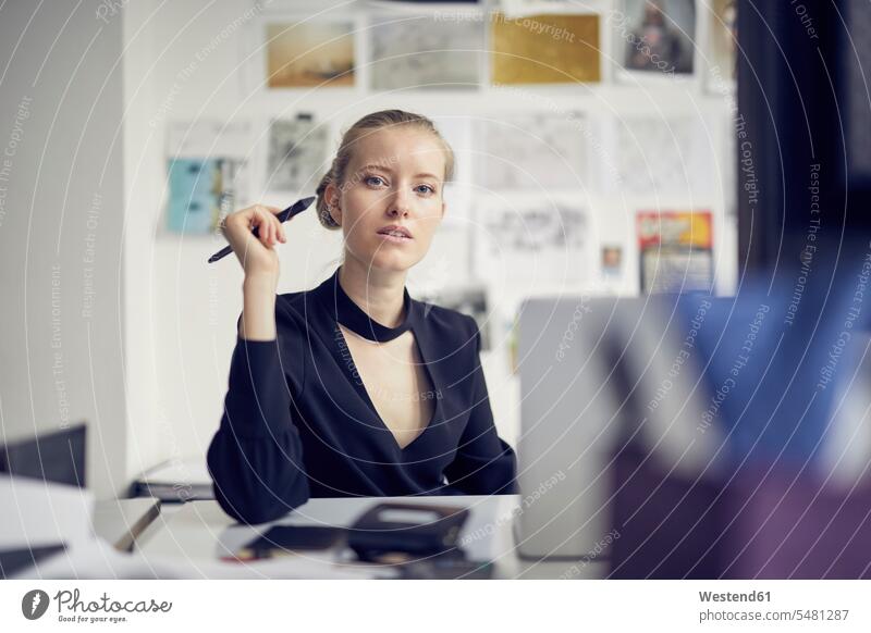 Portrait of young businesswoman at desk in the office businesswomen business woman business women portrait portraits offices office room office rooms