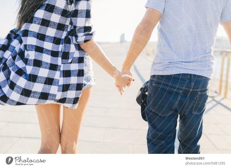 Young couple holding hands, rear view human hand human hands hand in hand back view view from the back young twosomes partnership couples in love people persons