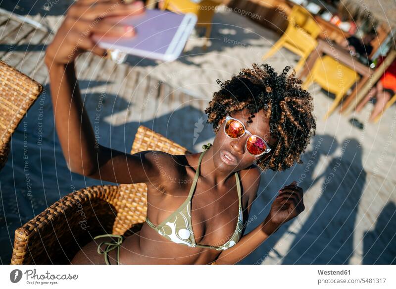 Young woman taking a selfie with a smartphone in a beach bar Selfie Selfies beaches females women Adults grown-ups grownups adult people persons human being