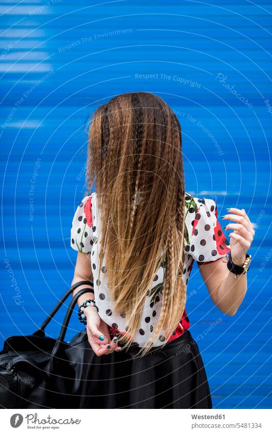 Braided hair of stilished young woman in front of blue roller shutter fashion fashionable females women people persons human being humans human beings Adults