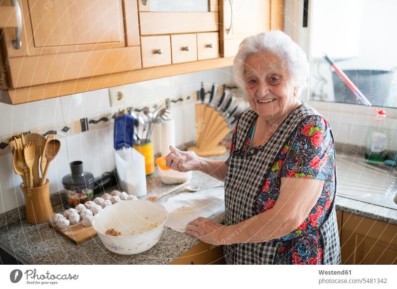 Portrait of smiling senior woman preparing meatballs in the kitchen domestic kitchen kitchens senior women elder women elder woman old portrait portraits