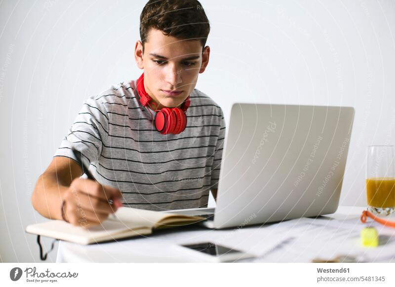 Teenage boy doing homeworks with laptop Teenager Teens teenagers Home work learning people persons human being humans human beings working At Work writing write