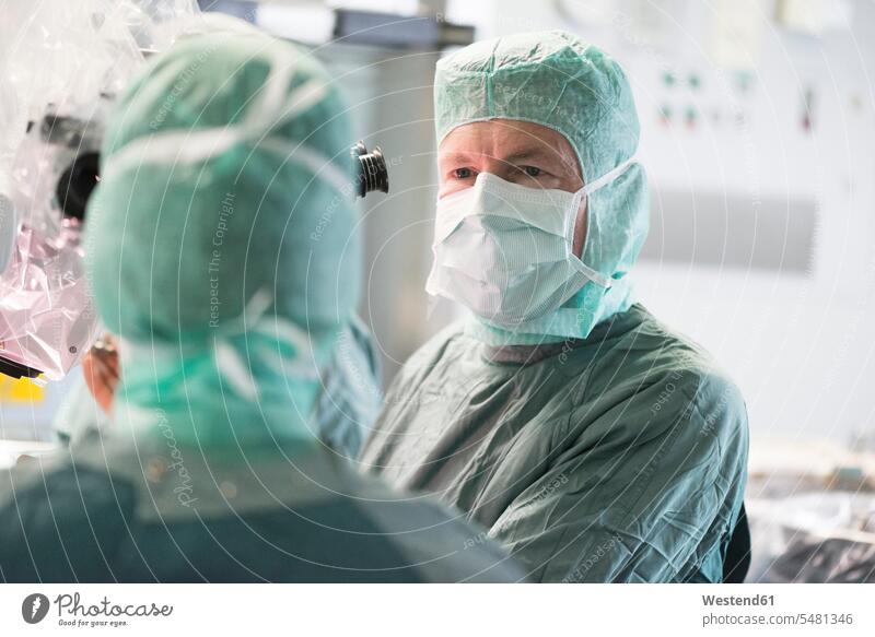 Neurosurgeon consulting colleague during an operation colleagues surgery surgeries operating doctor physicians doctors treatment Medical Treatment treatments