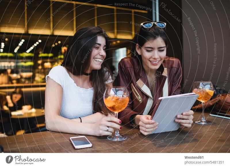 Two happy young women looking at tablet in a bar digitizer Tablet Computer Tablet PC Tablet Computers iPad Digital Tablet digital tablets female friends smiling