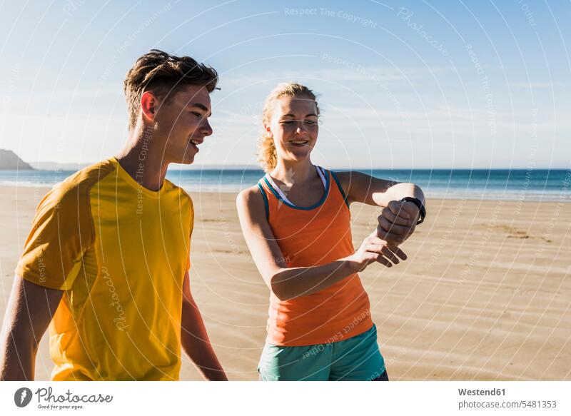 France, Crozon peninsula, sportive young couple on the beach looking at watch wrist watch Wristwatch Wristwatches wrist watches beaches twosomes partnership