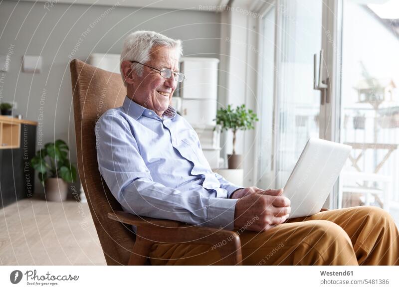 Portrait of senior man sitting on armchair at home using laptop caucasian caucasian ethnicity caucasian appearance european confidence confident relaxed
