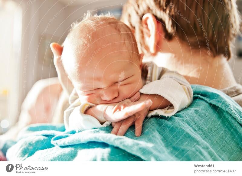 Close-up of father holding his newborn son over the shoulder pa fathers daddy dads papa babies infants baby sons manchild manchildren parents family families