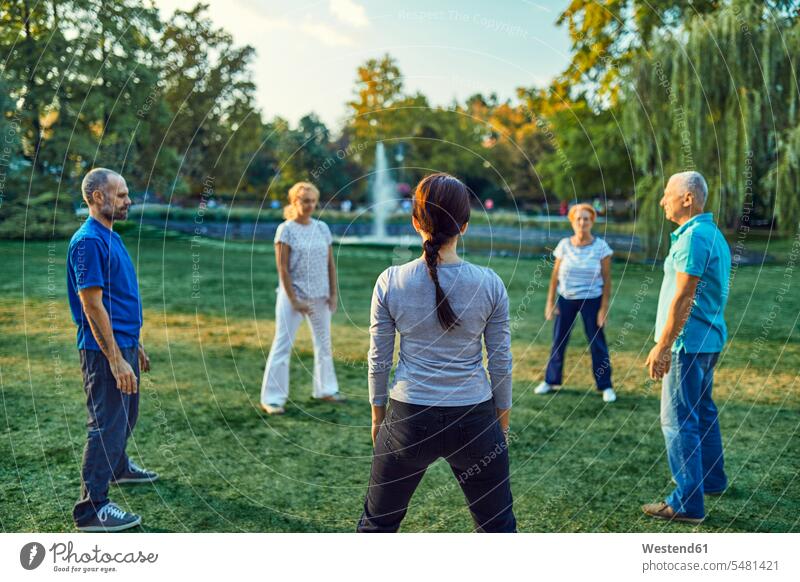 Group of people doing Tai chi in a park training partner training partners athlete sportswoman athletes female athlete sportswomen female athletes Taijiquan