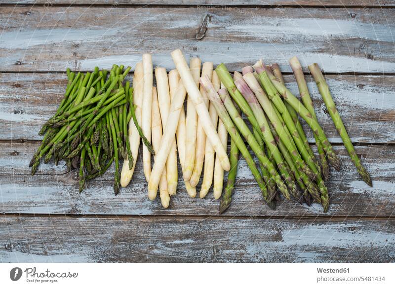 Green and white asparagus on wood uncooked wooden raw large group of objects many objects green Vegetable Vegetables nobody Asparagus Asparagi