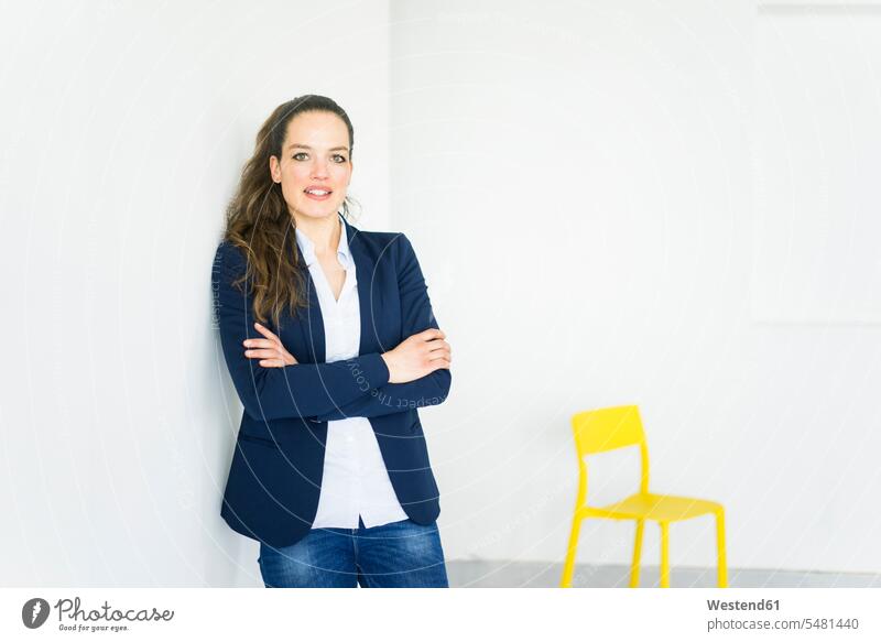 Portrait of businesswoman in a room with yellow chair females women businesswomen business woman business women standing Adults grown-ups grownups adult people