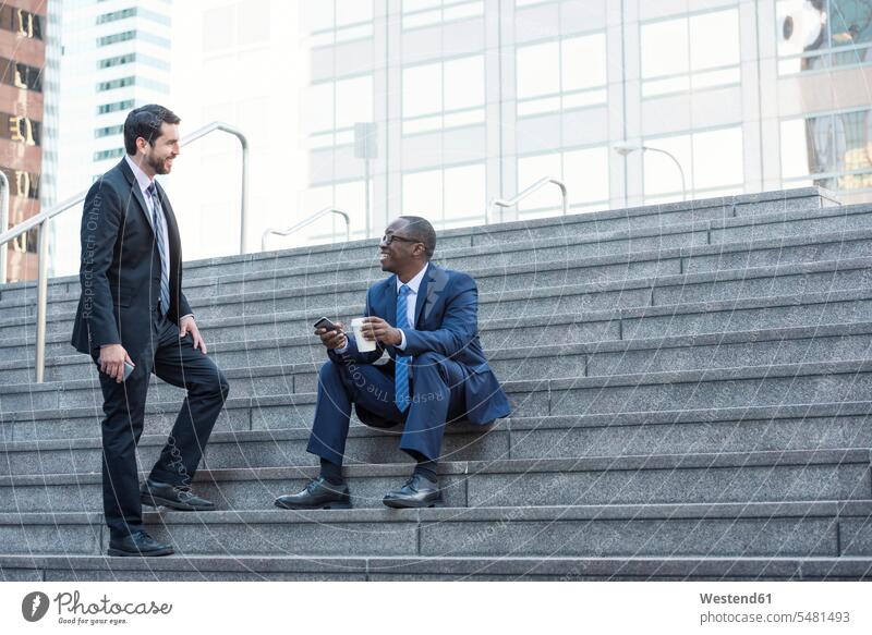 Two businessmen talking on stairs Businessman Business man Businessmen Business men stairway colleagues speaking business people businesspeople business world