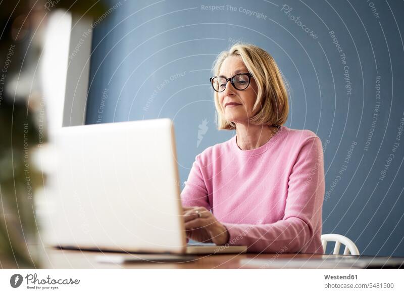 Mature woman using laptop at home Laptop Computers laptops notebook females women computer computers Adults grown-ups grownups adult people persons human being