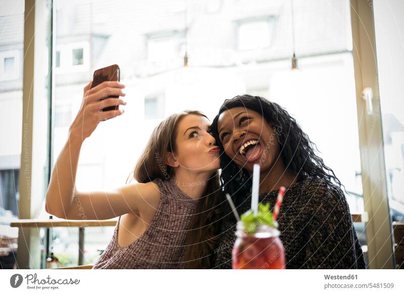 Two young women taking selfie in a cafe female friends meeting encounter gathering Fun having fun funny together Selfie Selfies Smartphone iPhone Smartphones