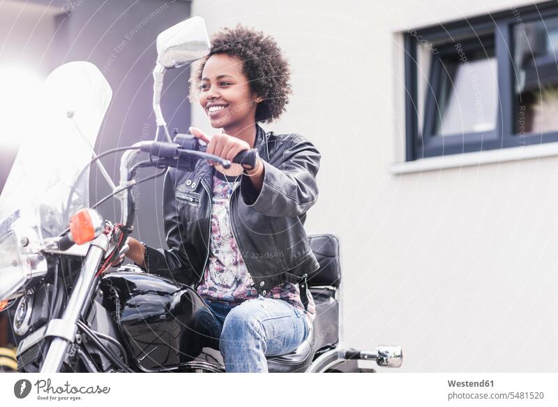 Smiling young woman on her motorcycle females women smiling smile motorbike Motor Cycle Adults grown-ups grownups adult people persons human being humans
