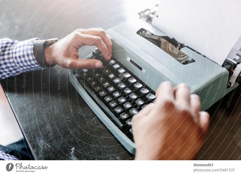 Close-up of man at desk using typewriter men males desks typewriters Adults grown-ups grownups adult people persons human being humans human beings Table Tables