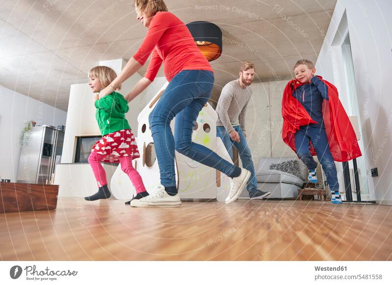 Happy family running in living room Germany mid adult men mid adult man mid-adult men mid-adult man young women young woman boy boys males girl females girls