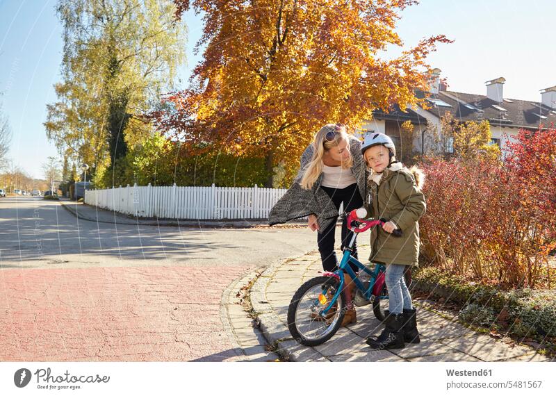 Mother talking to daughter with bicycle daughters bikes bicycles mother mommy mothers ma mummy mama security safe Safety secure child children family families