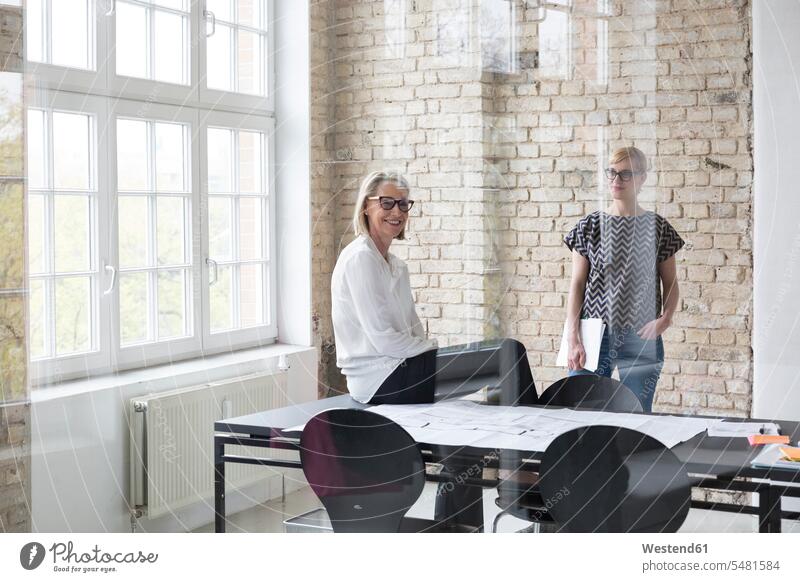 Mature businesswoman working with younger colleague in office learning sharing share Blueprint Blueprints Building Plan architectural drawing Construction Plan