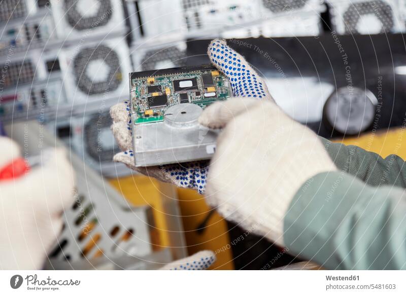 Worker holding hard disk in computer recycling plant ecology recycle harddrive hard drive working At Work hand human hand hands human hands worker