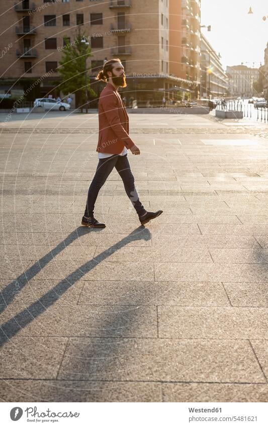 Fashionable young man walking on a square going men males Adults grown-ups grownups adult people persons human being humans human beings plaza places