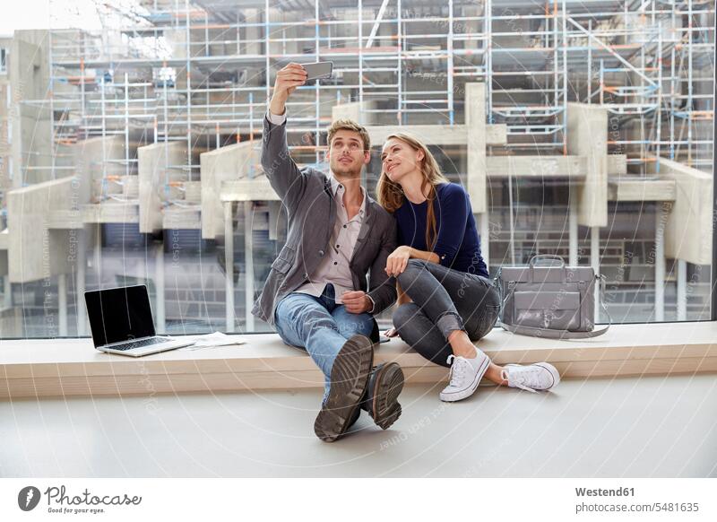Young couple sitting at the window taking a selfie smiling smile twosomes partnership couples Selfie Selfies mobile phone mobiles mobile phones Cellphone