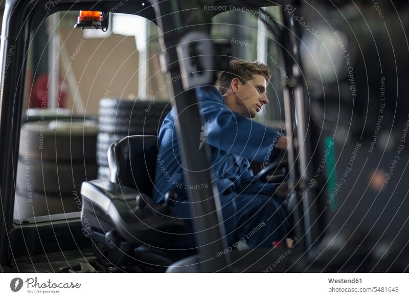 Factory working driving a fork lift in warehouse factory forklift forklifts forklift truck forklift trucks storehouse storage worker blue collar worker workers