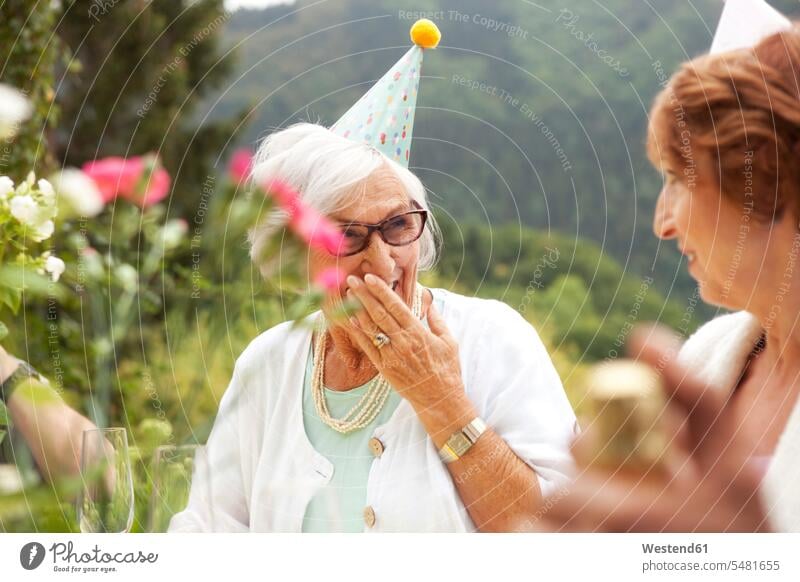 Senior ladies laughing at celebration, wearing party hats drinking tipsy Sparkling Wine champagne cheerful gaiety Joyous glad Cheerfulness exhilaration merry
