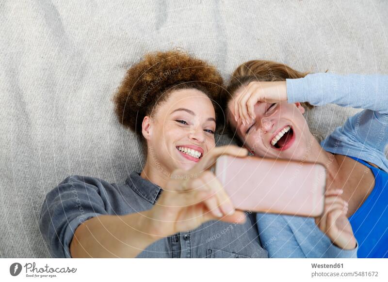 Two happy young women taking a selfie on blanket female friends smiling smile Selfie Selfies woman females mate friendship Adults grown-ups grownups adult