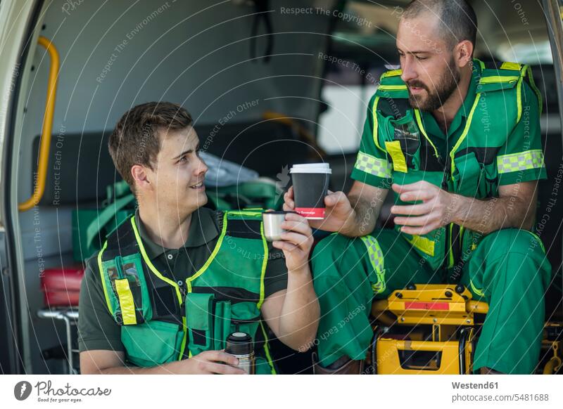 Paramedics taking a break sitting in the back of ambulance paramedic paramedics drinking Taking a Break resting Coffee healthcare and medicine medical