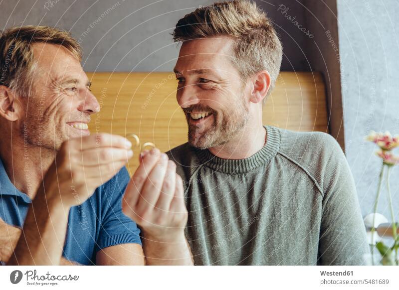 Happy gay couple holding up their wedding rings marrying smiling smile Love loving twosomes partnership couples talking speaking gay men gay man homosexual men