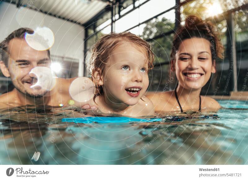 Happy parents with daughter in indoor swimming pool swimming bath portrait portraits daughters happiness happy indoor swimming pools family families people