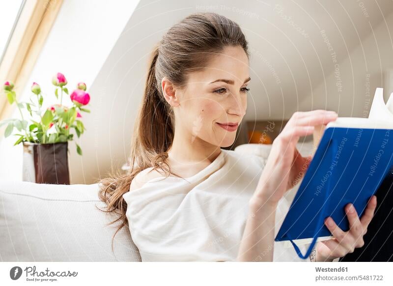 Smiling young woman reading book females women books Adults grown-ups grownups adult people persons human being humans human beings smiling smile caucasian