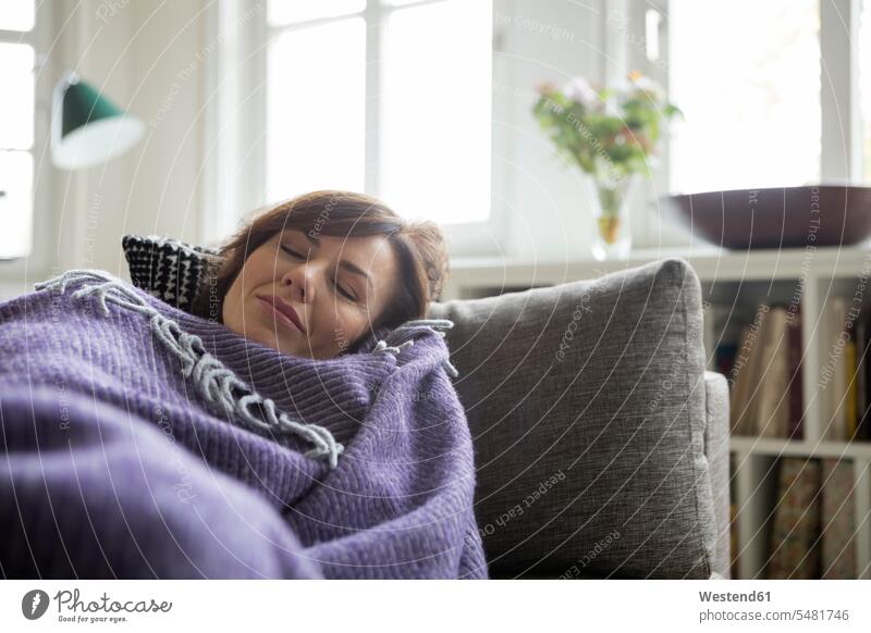 Woman with blanket lying on the sofa woman females women laying down lie lying down couch settee sofas couches settees ill sick sleeping asleep Blanket Blankets