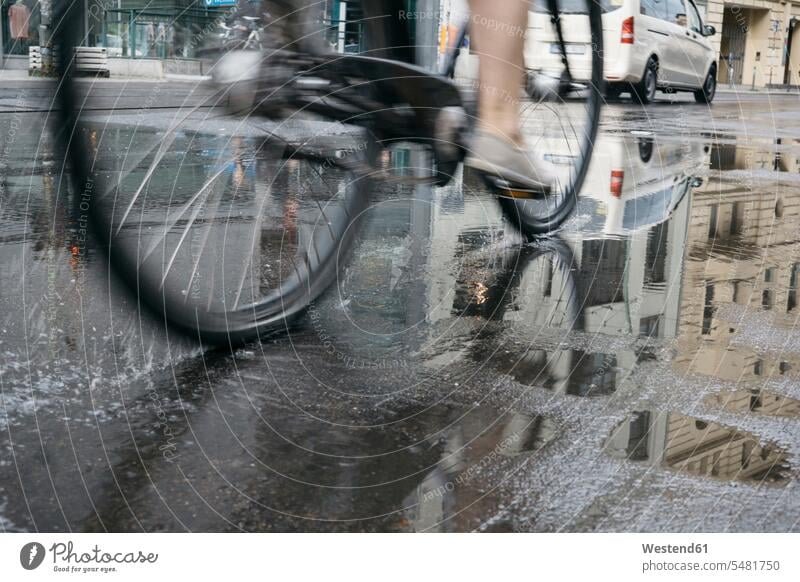 Riding bicycle in the city on a rainy day, partial view bikes bicycles street streets City Street City Streets tarmac asphalt Blacktop low section Waist Down