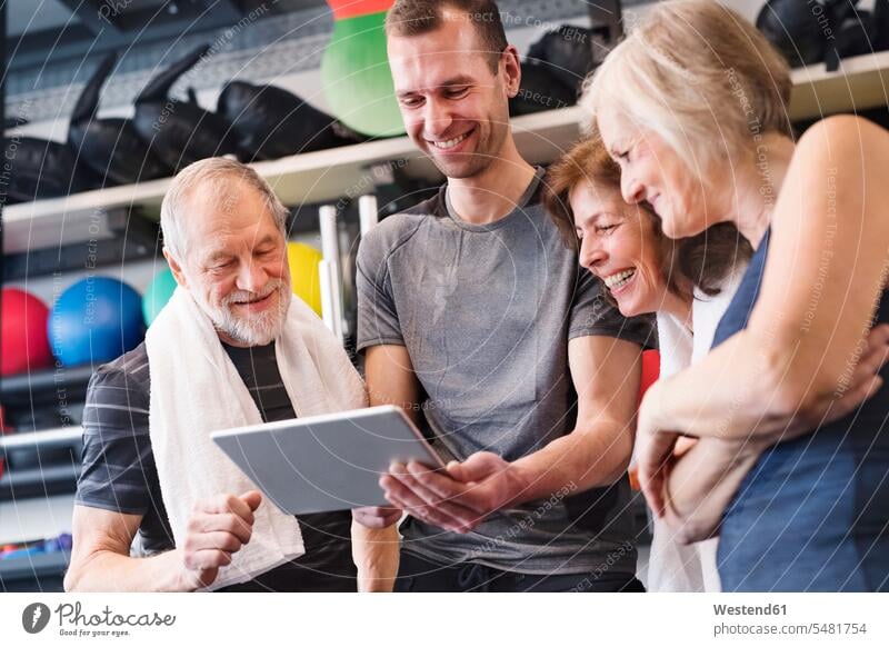 Group of fit seniors and personal trainer in gym looking at tablet gyms Health Club digitizer Tablet Computer Tablet PC Tablet Computers iPad Digital Tablet